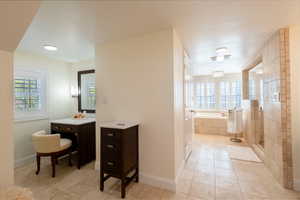 Bathroom featuring a bath, a shower stall, light tile patterned floors, and vanity