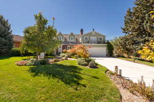 View of front of home featuring concrete driveway, a front lawn, a chimney, and a garage