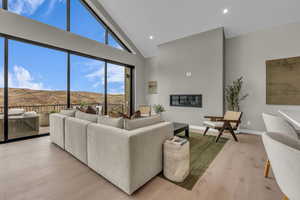 Living area featuring high vaulted ceiling, a mountain view, light wood finished floors, recessed lighting, and a glass covered fireplace