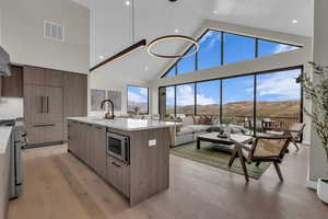 Kitchen featuring high vaulted ceiling, a mountain view, modern cabinets, light stone counters, and stainless steel appliances