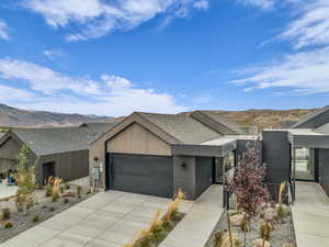 View of front of home with a mountain view, a garage, concrete driveway, and roof with shingles