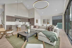 Living area featuring high vaulted ceiling, light wood-style floors, and recessed lighting