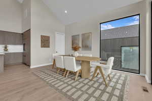 Dining space featuring high vaulted ceiling, light wood-style flooring, and recessed lighting