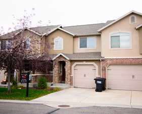 Traditional-style home with stucco siding, a garage, driveway, a shingled roof, and stone siding