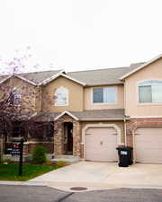 Traditional home with stucco siding, driveway, a garage, and a shingled roof