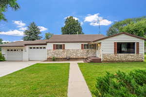 Ranch-style home with a front lawn, stone siding, and roof with shingles