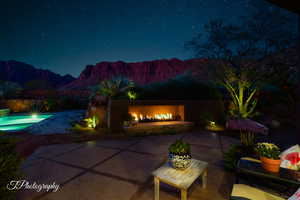 Patio at twilight featuring a patio and a warm lit fireplace
