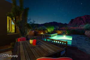 Pool at night featuring outdoor dining space, a patio area, and a deck
