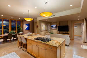Kitchen featuring recessed lighting, open floor plan, light brown cabinets, light stone countertops, and pendant lighting