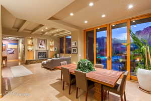 Dining space featuring beam ceiling, a stone fireplace, recessed lighting, light tile patterned flooring, and french doors