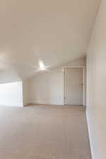 Empty room with light carpet and vaulted ceiling