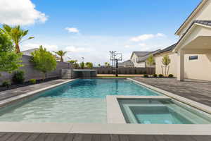 View of pool with a patio, a fenced backyard, and a pool with connected hot tub