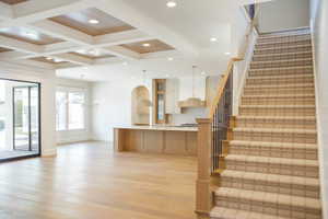 Stairs featuring beam ceiling, wood finished floors, a chandelier, recessed lighting, and coffered ceiling