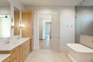 Full bath with a freestanding bath, double vanity, a stall shower, and light tile patterned floors