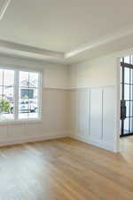 Spare room featuring a decorative wall, light wood-style flooring, plenty of natural light, and a wainscoted wall