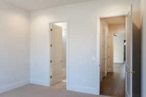 Unfurnished bedroom featuring connected bathroom and light carpet