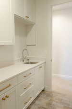 Kitchen with white cabinetry, light stone counters, and wood finish floors