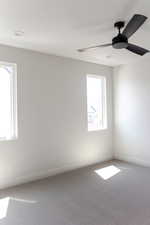Carpeted empty room featuring baseboards and a ceiling fan