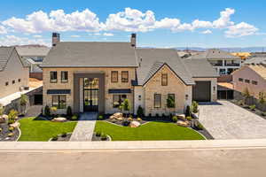 View of front of house featuring stone siding, a residential view, a chimney, decorative driveway, and an attached garage