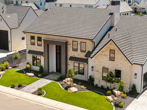 View of front of house with stone siding, a front lawn, and a chimney
