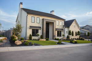 View of front of house featuring stone siding, a chimney, a standing seam roof, and a metal roof