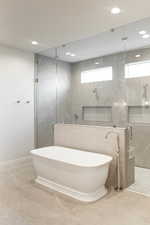 Bathroom featuring a marble finish shower, a freestanding tub, tile walls, recessed lighting, and tile patterned floors