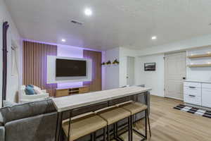 Kitchen with light wood-type flooring, a textured ceiling, light countertops, open shelves, and white cabinets