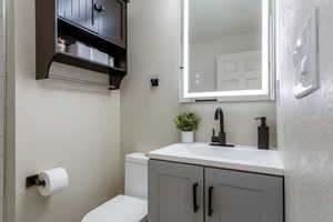 Half bath with a textured wall and vanity