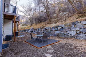 View of yard featuring a patio area, outdoor dining area, a balcony, and view of scattered trees
