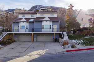 View of front of home with stairs, driveway, brick siding, and an attached garage