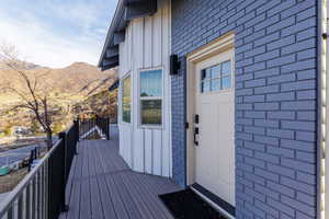 View of exterior entry featuring board and batten siding, brick siding, and a deck with mountain view