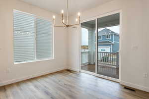 Unfurnished dining area featuring a chandelier and light wood-type flooring