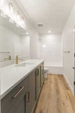 Bathroom featuring vanity, washtub / shower combination, and light wood-style floors