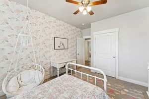Carpeted bedroom with wallpapered walls and ceiling fan
