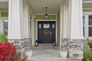 Property entrance with stone siding and covered porch