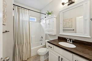 Full bath with shower / bath combo with shower curtain, vanity, and light tile patterned floors