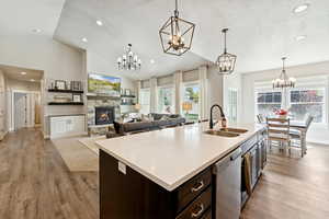 Kitchen with a fireplace, recessed lighting, dark brown cabinets, a kitchen island with sink, and stainless steel dishwasher