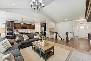 Living room featuring a chandelier, lofted ceiling, recessed lighting, and light wood-style flooring