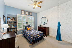 Bedroom with carpet floors, ceiling fan, and wallpapered walls