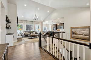 Corridor featuring a chandelier, an upstairs landing, recessed lighting, dark wood-type flooring, and high vaulted ceiling