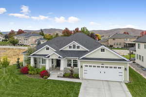 Craftsman house with roof with shingles, a front yard, a mountain view, driveway, and an attached garage