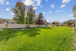 Fenced backyard featuring a trampoline, a patio, a playground, and a mountain view