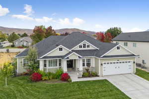 Craftsman-style house featuring roof with shingles, a front yard, driveway, an attached garage, and a mountain view