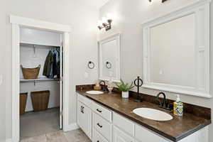 Full bath with double vanity, light tile patterned flooring, and a spacious closet