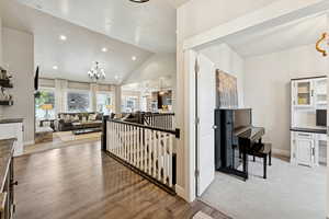 Hallway with an upstairs landing, recessed lighting, a chandelier, light wood finished floors, and high vaulted ceiling
