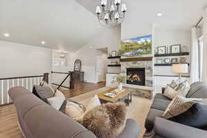 Living area featuring a chandelier, wainscoting, wood finished floors, recessed lighting, and high vaulted ceiling