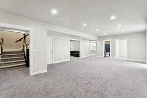 Below grade area with light colored carpet, stairs, and recessed lighting