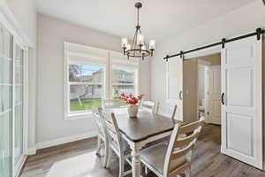 Dining room with a barn door, a chandelier, and light wood-style floors