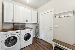 Washroom with dark wood-style flooring, washer and dryer, and cabinet space
