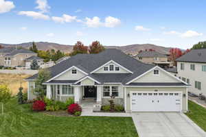 Craftsman house featuring a shingled roof, driveway, a mountain view, and a front lawn